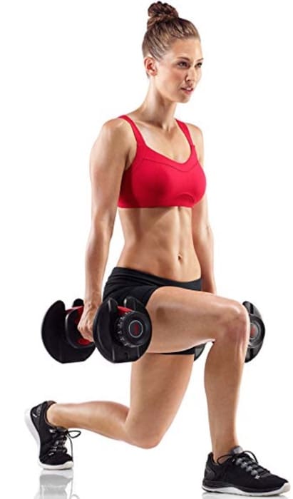 a woman does split squats with her bowflex dumbbells